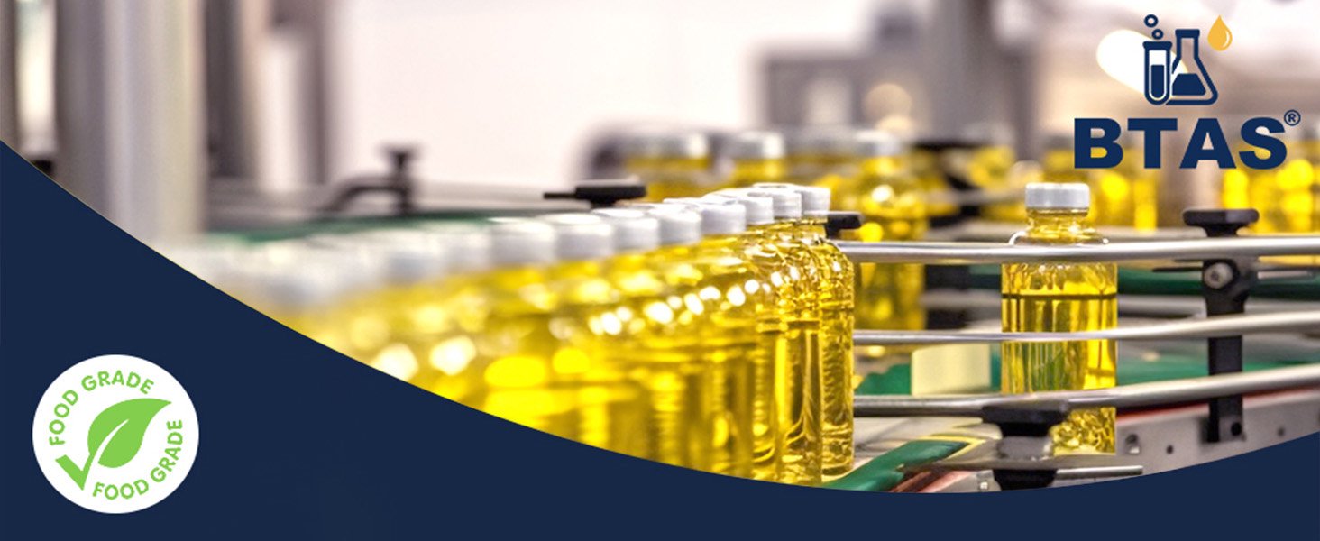 BTAS brand banner showing rows of bottles filled with yellow liquid on a conveyor belt in a factory, featuring a green Food Grade certification icon.